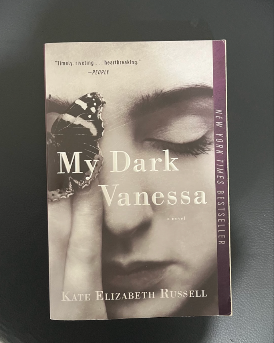 This photo features the cover of "My Dark Vanessa". The cover features Vanessa with her eyes closed, symbolism alluding to the nature of her perception of her relationship, as she is unaware of what actually happened. The butterfly is also a prominent motif throughout the book, symbolizing transformation and growth as Vanessa comes to terms with the reality of her past throughout the book.